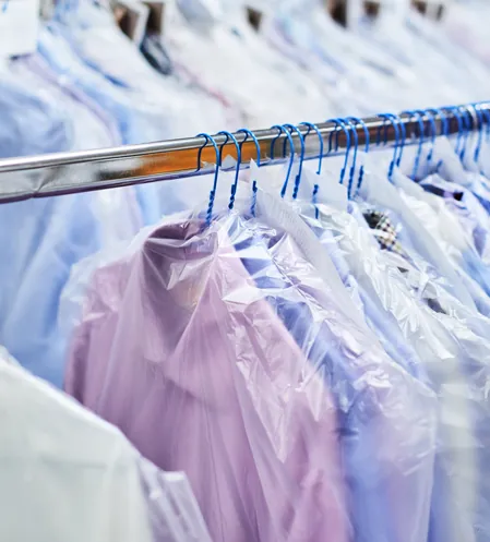 Pressed shirts in garment bags hanging on a rack
