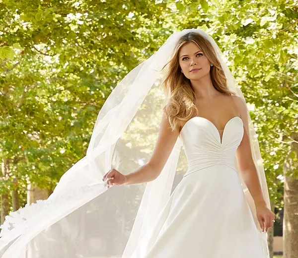 Bride in a white strapless wedding gown and veil outdoors